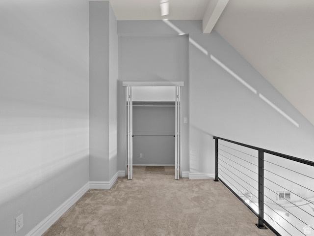 interior space with carpet, a closet, baseboards, and lofted ceiling with beams