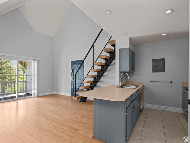 kitchen featuring baseboards, a sink, high vaulted ceiling, electric panel, and light countertops