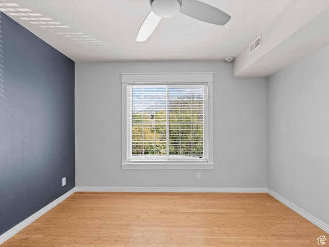 spare room with visible vents, wood finished floors, baseboards, and ceiling fan