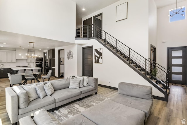 423 W Red Wolf Dr, Saratoga Springs, UT 84045 - living area featuring an inviting chandelier, light wood-type flooring, baseboards, a towering ceiling, and stairs