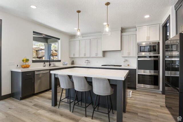 423 W Red Wolf Dr, Saratoga Springs, UT 84045 - kitchen with a center island, a sink, a kitchen breakfast bar, black appliances, and light countertops