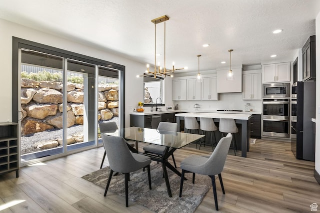 423 W Red Wolf Dr, Saratoga Springs, UT 84045 - dining space with light wood finished floors, a chandelier, recessed lighting, and a textured ceiling