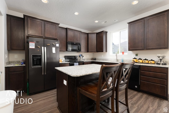 2034 E 970 N, Spanish Fork, UT 84660 - kitchen with black appliances, dark brown cabinetry, dark wood-style floors, a breakfast bar, and a kitchen island