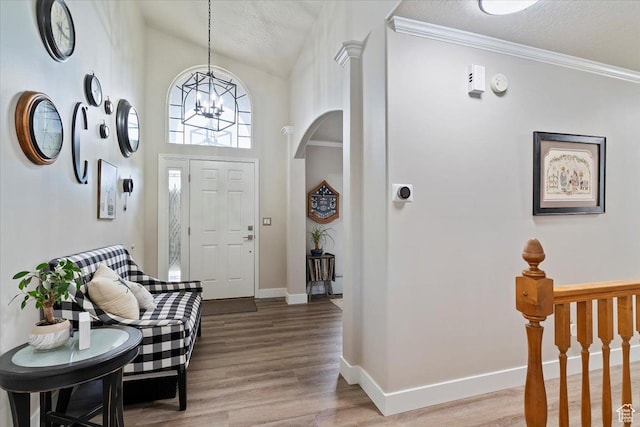 entryway featuring a chandelier, a high ceiling, baseboards, and light wood-type flooring