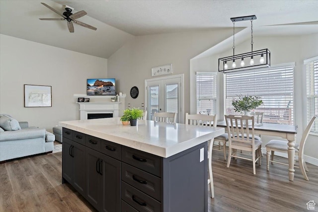 kitchen with lofted ceiling, dark wood-style flooring, ceiling fan, open floor plan, and a kitchen island