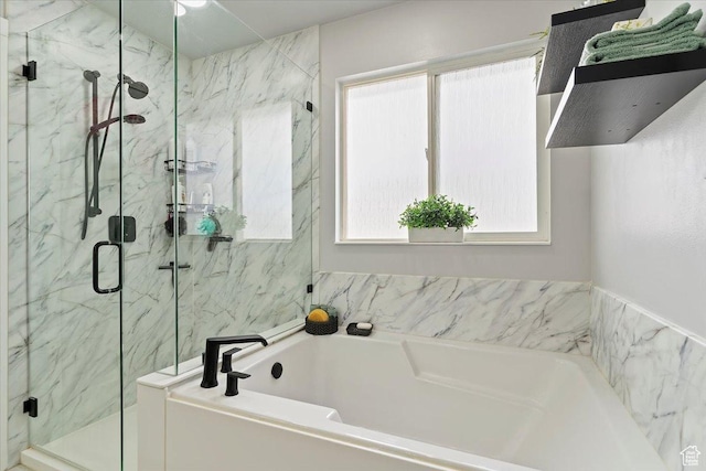 bathroom featuring a garden tub, plenty of natural light, and a marble finish shower