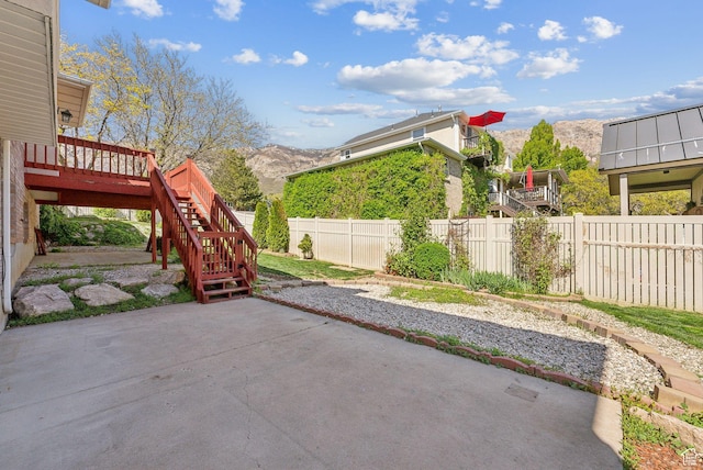 view of patio featuring a deck with mountain view, a fenced backyard, and stairs
