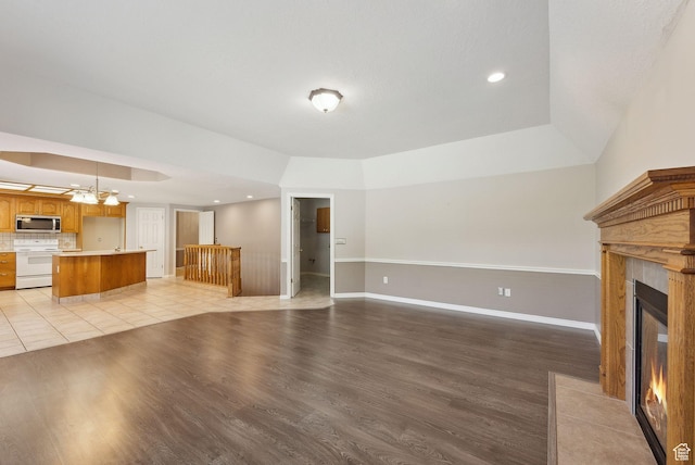 unfurnished living room featuring a premium fireplace, light wood-style flooring, baseboards, and recessed lighting