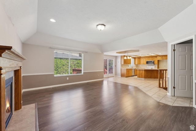 unfurnished living room with a textured ceiling, recessed lighting, light wood finished floors, a premium fireplace, and baseboards
