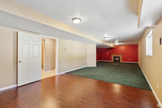 below grade area with baseboards, wood finished floors, and a fireplace