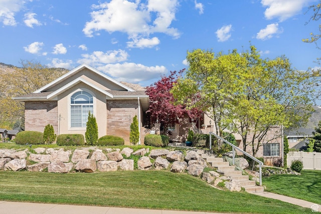 exterior space with a front lawn, brick siding, stairway, and fence