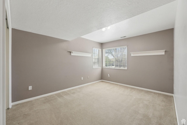 carpeted empty room featuring baseboards, visible vents, and a textured ceiling