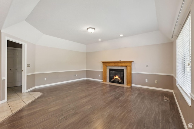 unfurnished living room featuring a tiled fireplace, wood finished floors, baseboards, and recessed lighting