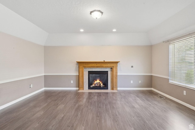 unfurnished living room featuring wood finished floors, recessed lighting, vaulted ceiling, a fireplace, and baseboards