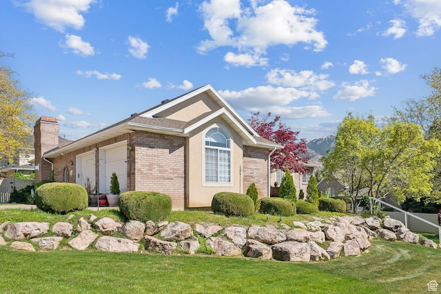 view of home's exterior with a yard, brick siding, a chimney, and an attached garage