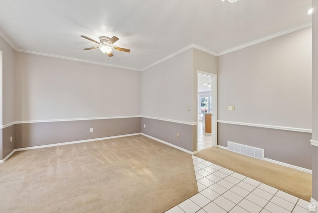 empty room with baseboards, ceiling fan, visible vents, crown molding, and light colored carpet