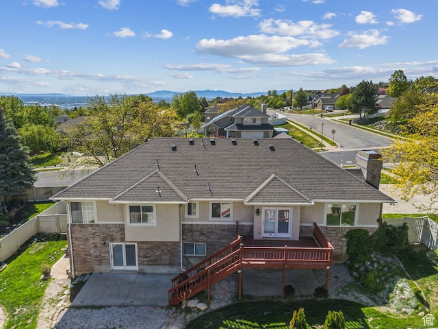 rear view of property featuring a deck with mountain view, a patio area, stucco siding, stairway, and a fenced backyard