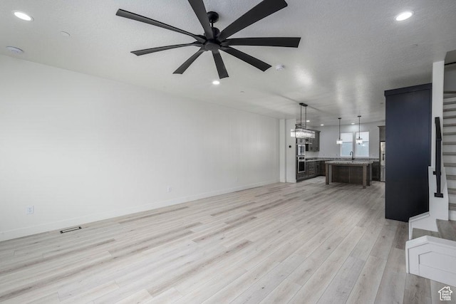 11056 S Lake Run Rd, South Jordan, UT 84009 - unfurnished living room featuring light wood finished floors, a ceiling fan, a sink, stairway, and recessed lighting