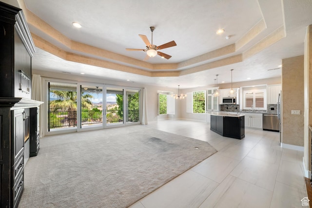 2996 S Limestone Dr, St George, UT 84790 - unfurnished living room featuring ceiling fan with notable chandelier, recessed lighting, a tray ceiling, baseboards, and a glass covered fireplace
