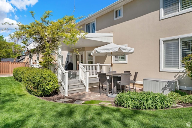 back of property with fence, a patio, stucco siding, and a lawn