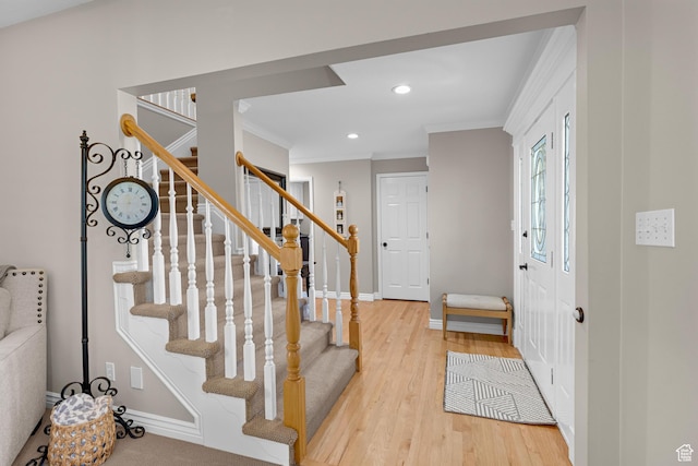 foyer entrance featuring crown molding, wood finished floors, baseboards, and stairs