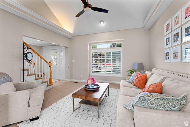 carpeted living room featuring a ceiling fan, baseboards, crown molding, vaulted ceiling, and stairway