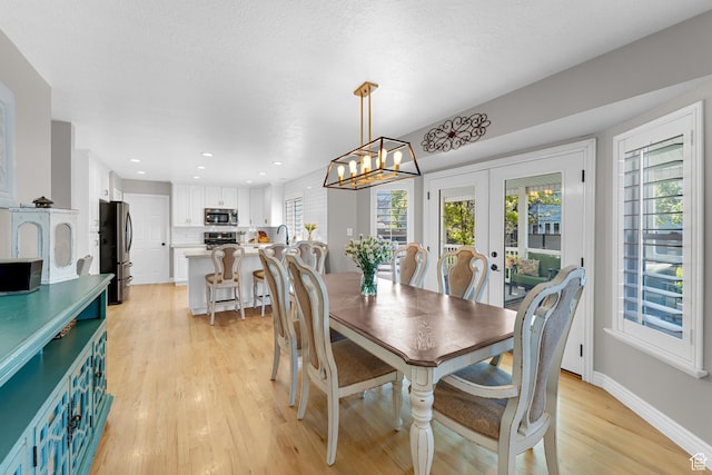 dining area featuring an inviting chandelier, plenty of natural light, french doors, and light wood-type flooring