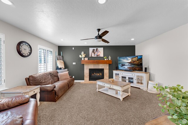 carpeted living room featuring recessed lighting, a tiled fireplace, ceiling fan, and a textured ceiling