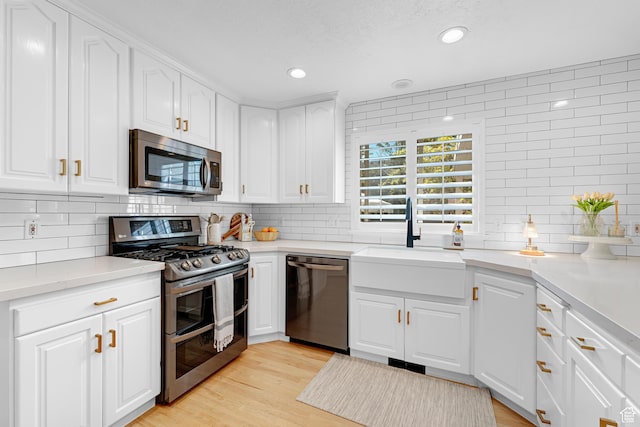 kitchen featuring backsplash, light wood-style floors, stainless steel appliances, and a sink