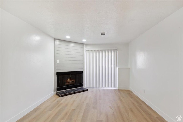 unfurnished living room featuring light wood-style floors, visible vents, a fireplace, and baseboards