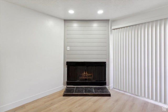 room details with recessed lighting, baseboards, a fireplace with raised hearth, and wood finished floors