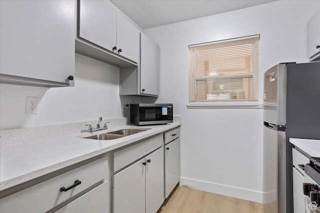 5630 S Meadow Ln E Unit 175, South Ogden, UT 84403 - kitchen featuring a sink, appliances with stainless steel finishes, light wood-style floors, baseboards, and white cabinets
