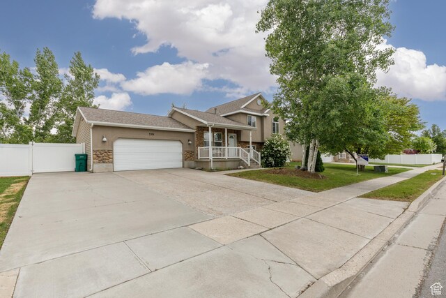 3391 W 1125 N, Layton, UT 84040 - split level home featuring stone siding, a garage, a porch, driveway, and stucco siding