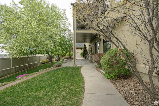 view of yard featuring fence and a balcony