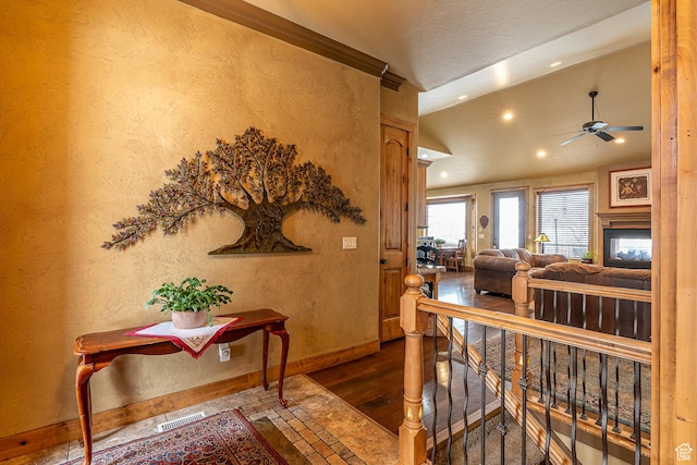 hall featuring wood finished floors, visible vents, baseboards, lofted ceiling, and recessed lighting