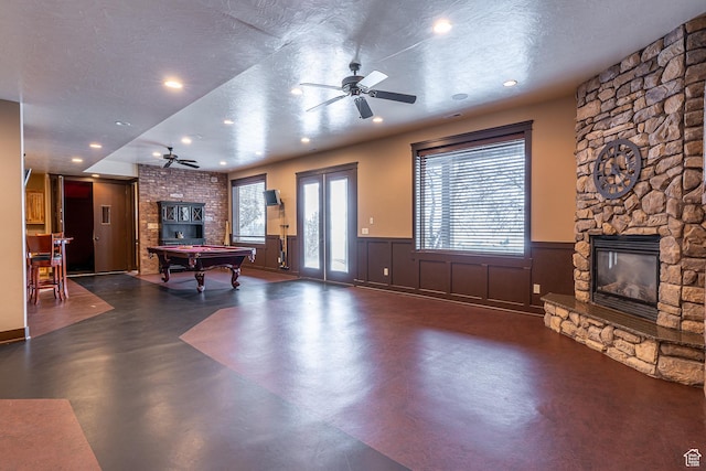 game room with a ceiling fan, billiards, a fireplace, and concrete flooring