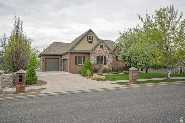 view of front facade featuring an attached garage, a front lawn, stone siding, and driveway
