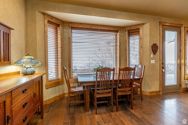 dining area featuring dark wood-style flooring, baseboards, and a textured wall