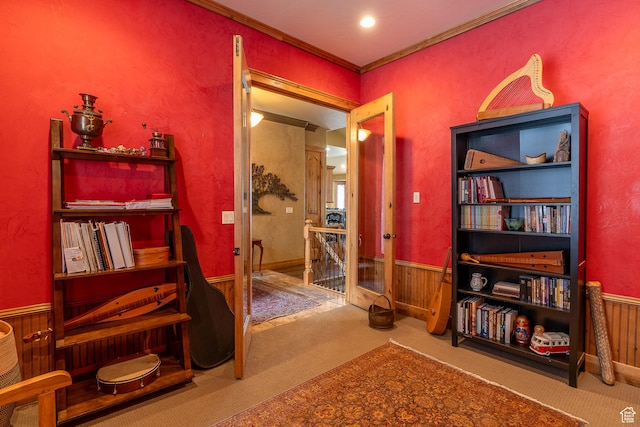 living area featuring wainscoting, crown molding, and carpet