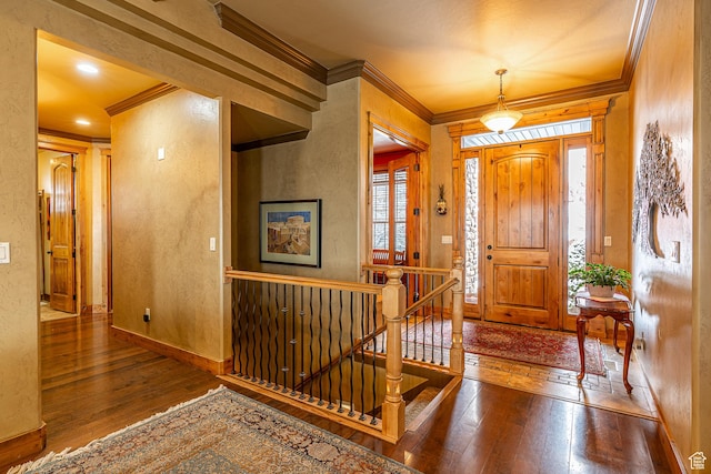 foyer entrance featuring crown molding, wood-type flooring, and baseboards