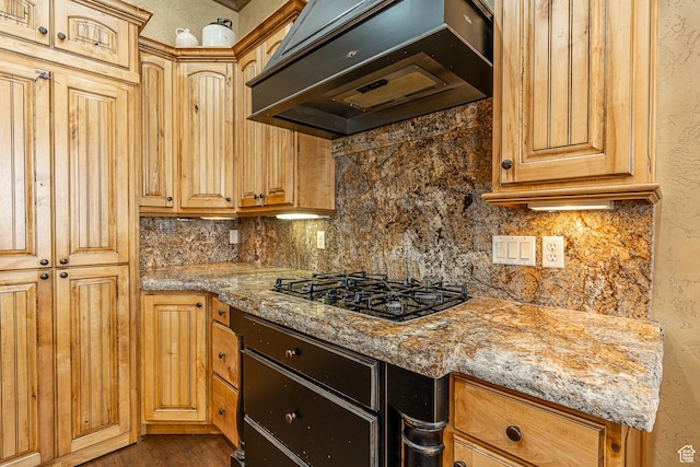 kitchen with under cabinet range hood, black gas cooktop, decorative backsplash, and light stone counters