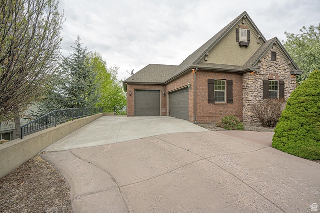 view of home's exterior with roof with shingles, fence, an attached garage, brick siding, and driveway