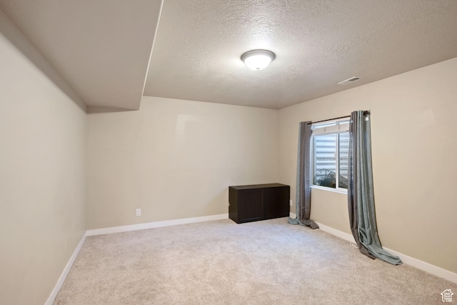 empty room featuring baseboards, light carpet, and a textured ceiling