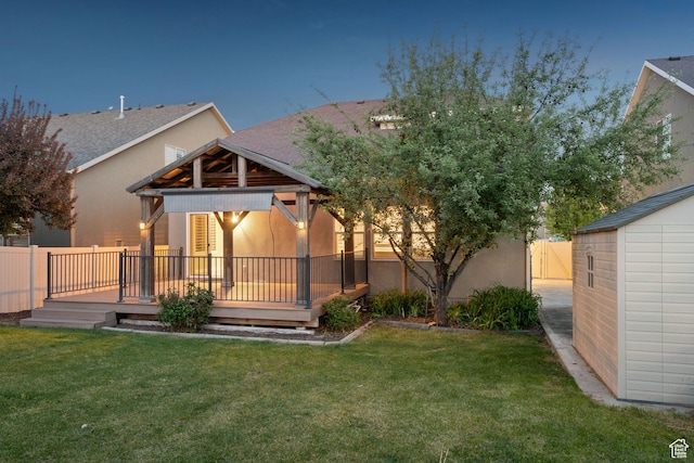 back of property featuring a yard, stucco siding, a deck, and a fenced backyard