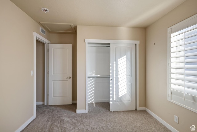 unfurnished bedroom featuring carpet, a closet, visible vents, and multiple windows