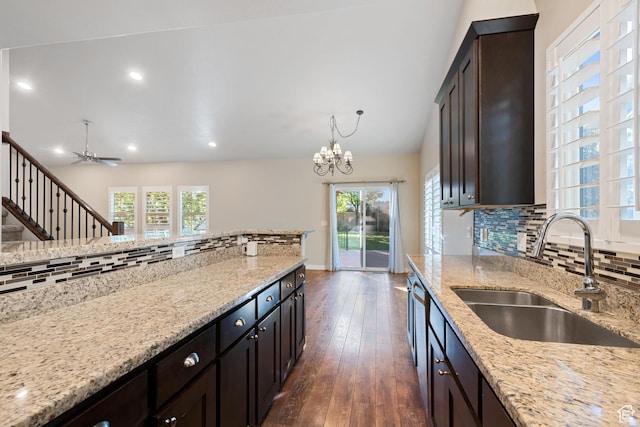 kitchen with backsplash, light stone counters, a sink, and dark wood-type flooring