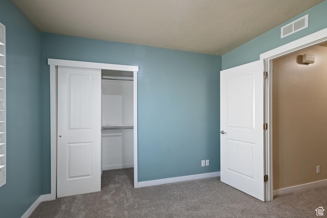 unfurnished bedroom featuring baseboards, carpet flooring, a closet, and visible vents
