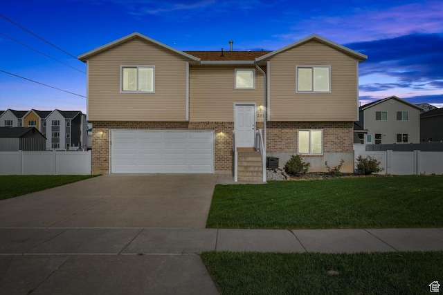 251 Sunstone Cir, Logan, UT 84321 - bi-level home featuring a lawn, brick siding, fence, an attached garage, and concrete driveway