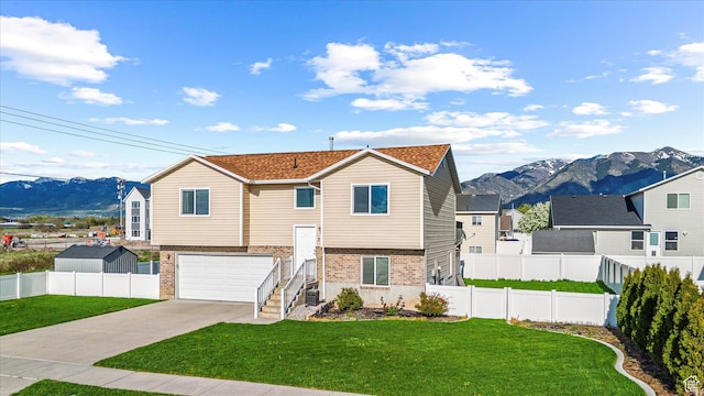 251 Sunstone Cir, Logan, UT 84321 - bi-level home with concrete driveway, a mountain view, brick siding, and a front yard