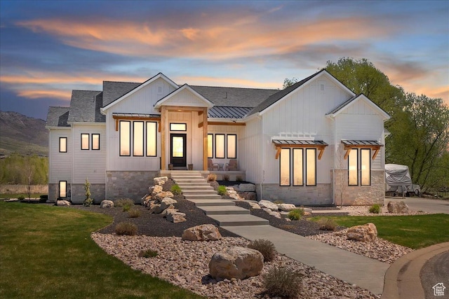modern inspired farmhouse featuring board and batten siding, a yard, metal roof, and a standing seam roof